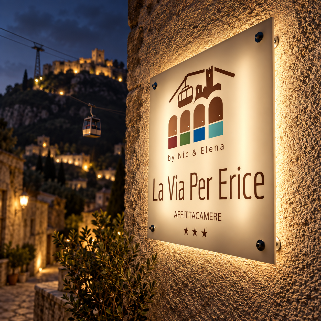 L’insegna illuminata di La Via Per Erice con il borgo e la funivia sullo sfondo